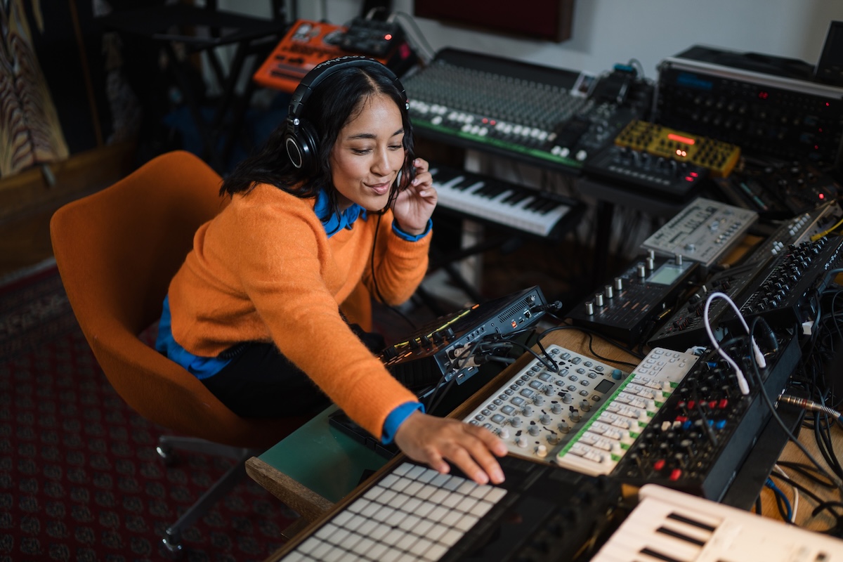 Asian woman producing electronic music in home studio