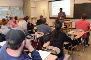 A person stands in front of a classroom of students.