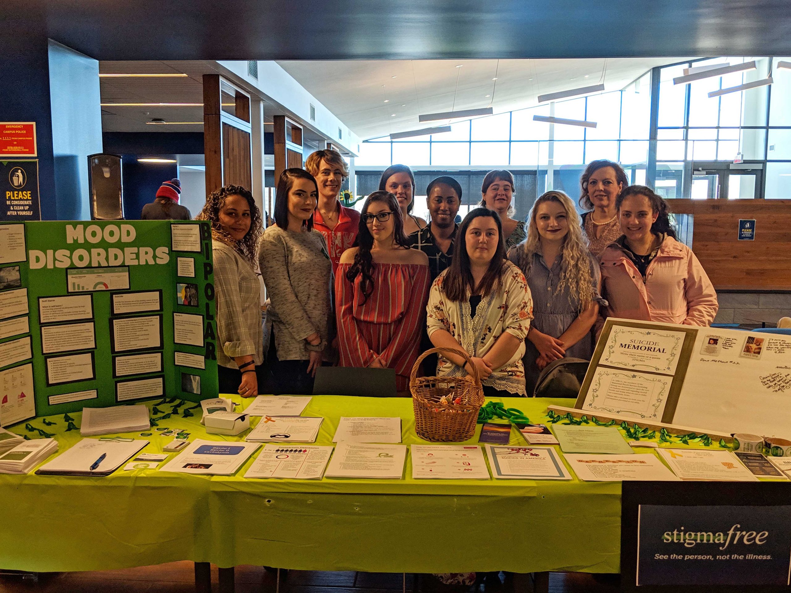 A group of people stands in front of a table covered with information and posters.