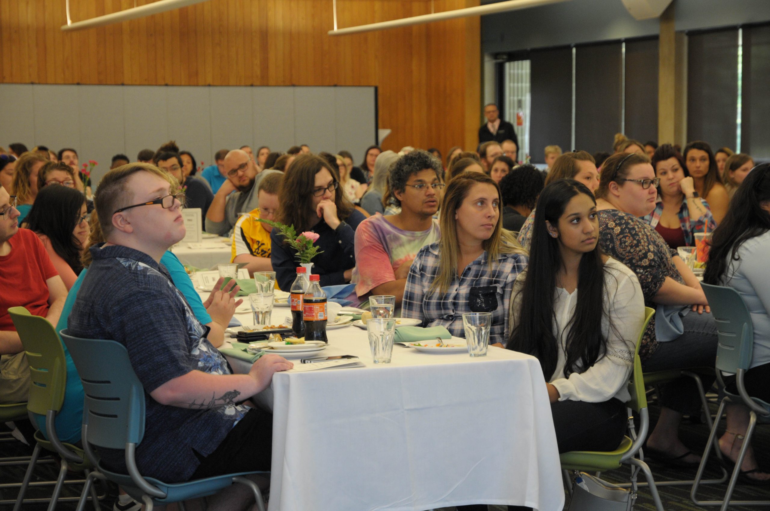 people sit at tables looking to the right. Listening. Learning.