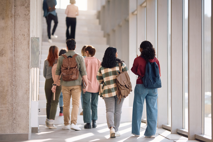Rear view of college students walking in a hallway.