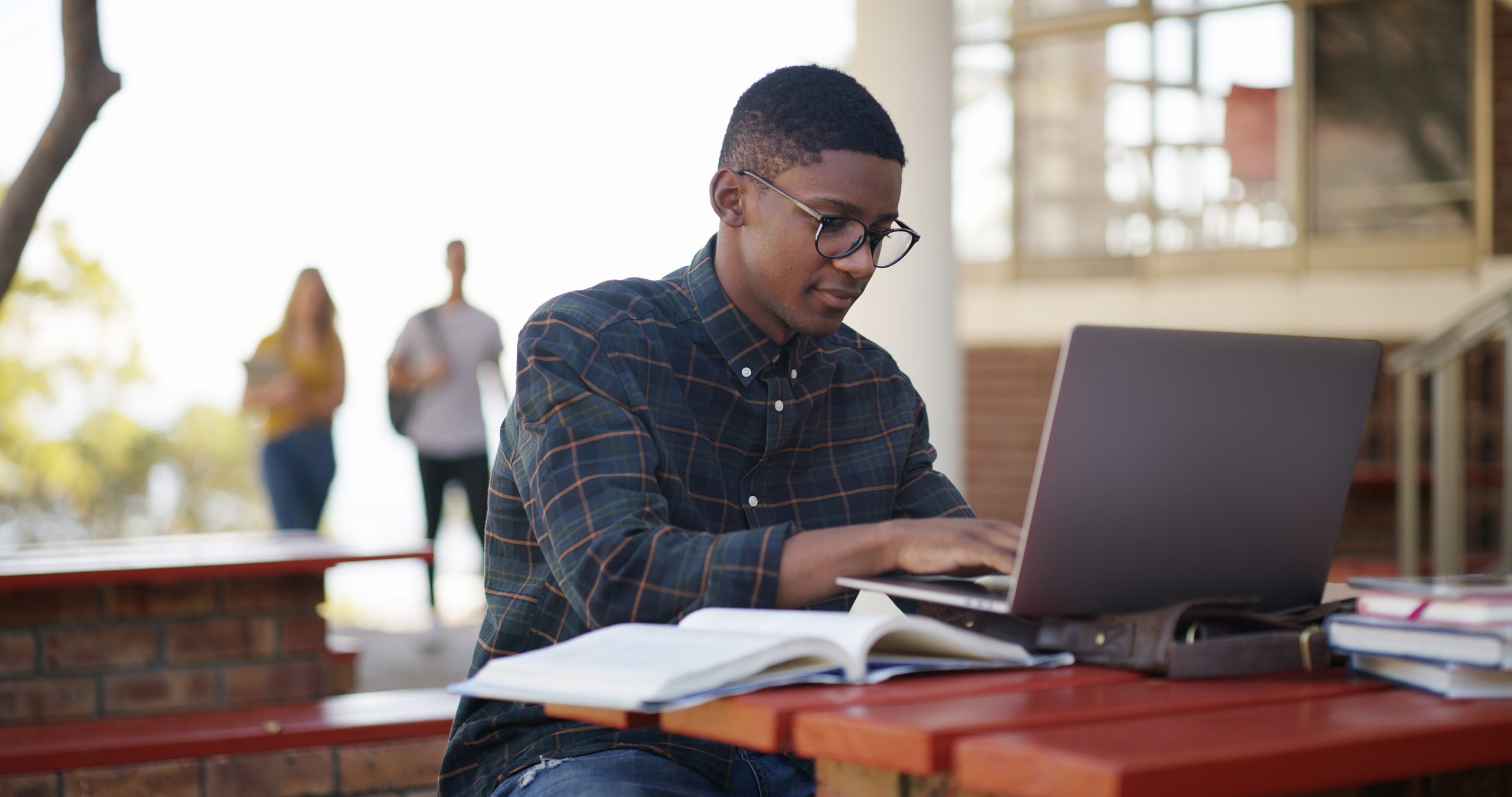 Student, typing and man in campus with laptop, test and research for project deadline. Preparation, multitask and scholar with study material, brainstorm and problem solve for academic goals.