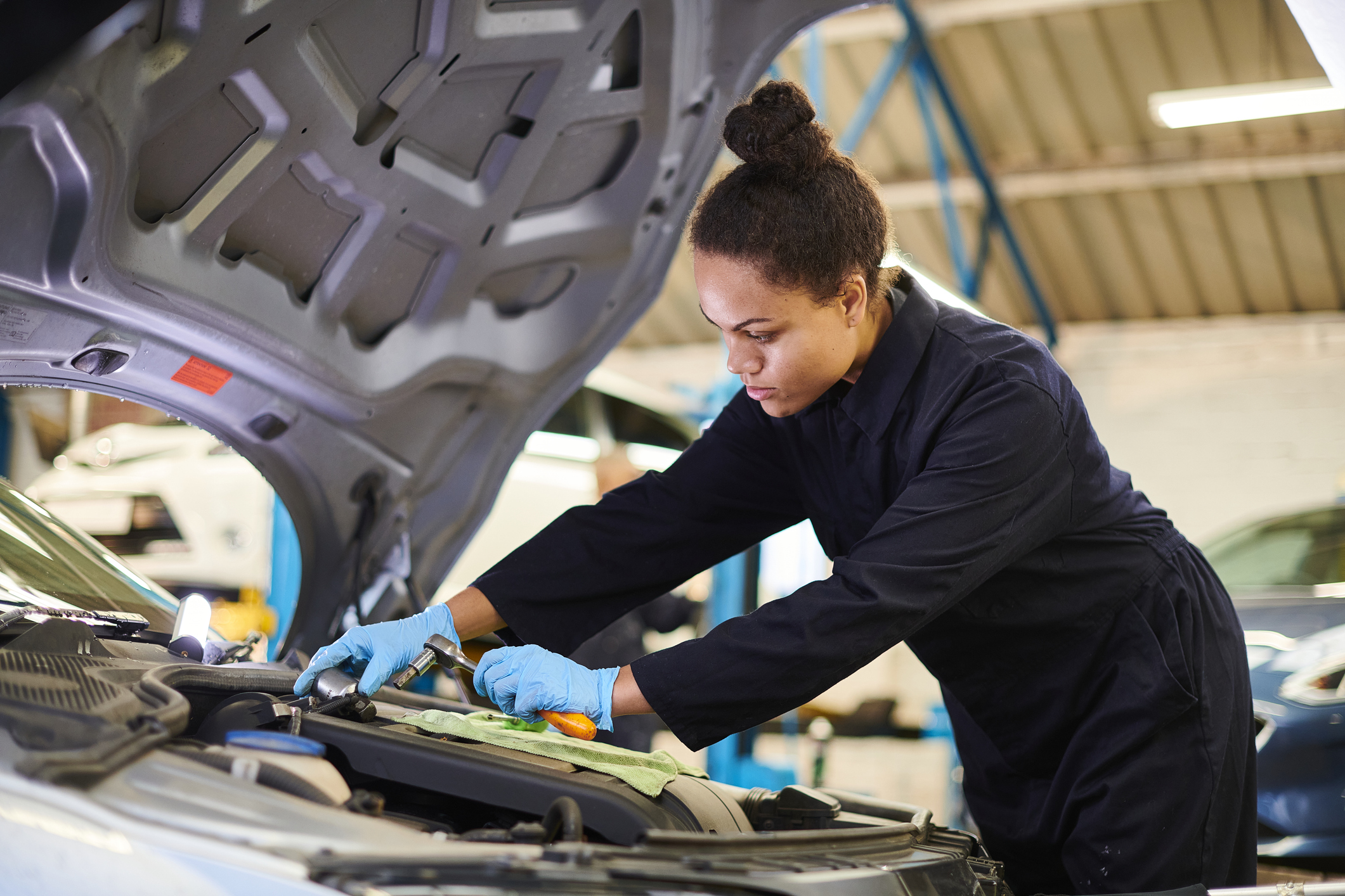 female apprentice mechanic underneath the bonnet