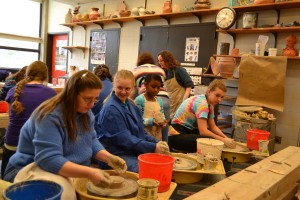 Four students working on pottery wheels