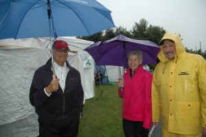 President Daniel Asquino, Chris Kisiel and Ed Terceiro in rain jackets and under umbrellas