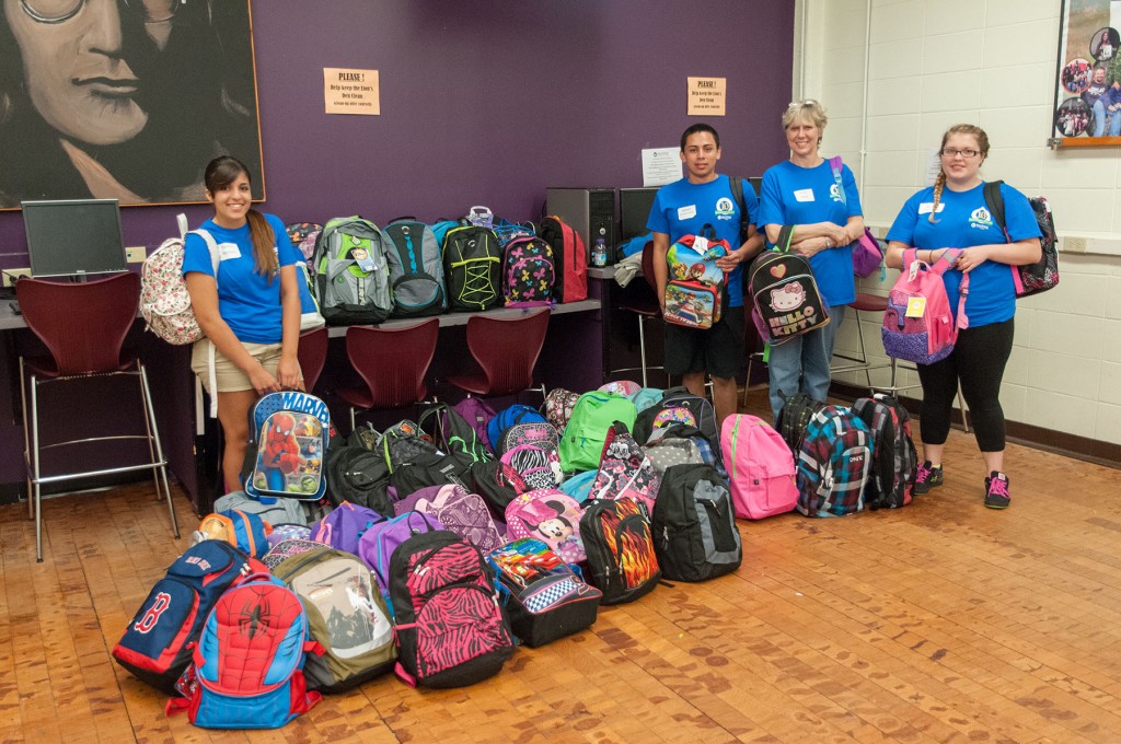 Group of student volunteers with the pile of backpacks that they put together