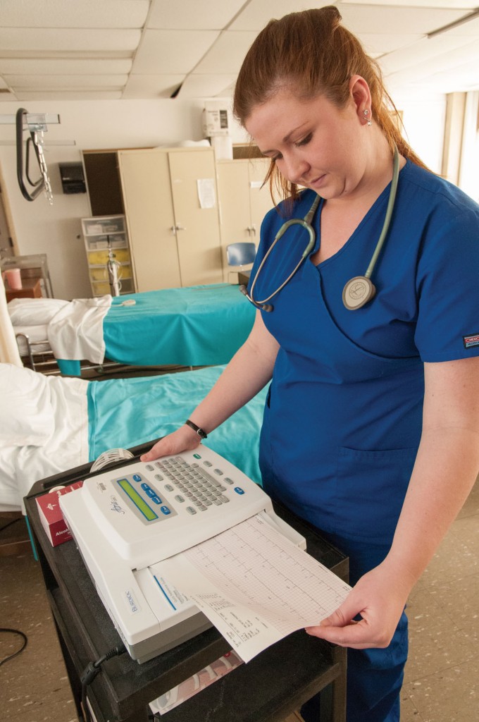 Medical Assisting student reading a chart in a simulated hospital room