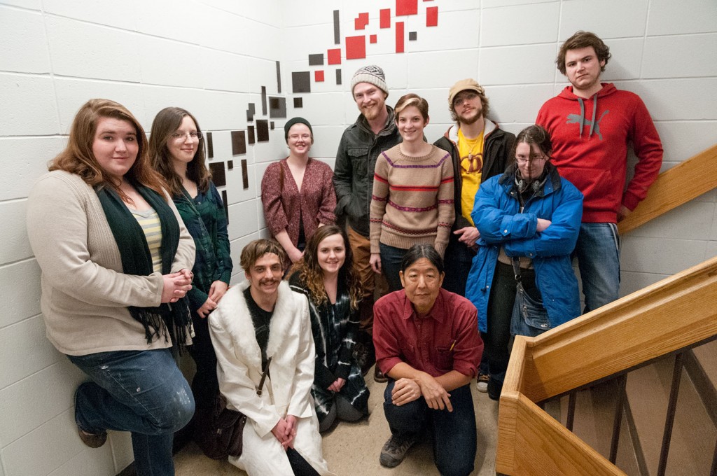 Group of art students standing in the stairwell in front of a red and black abstract installation