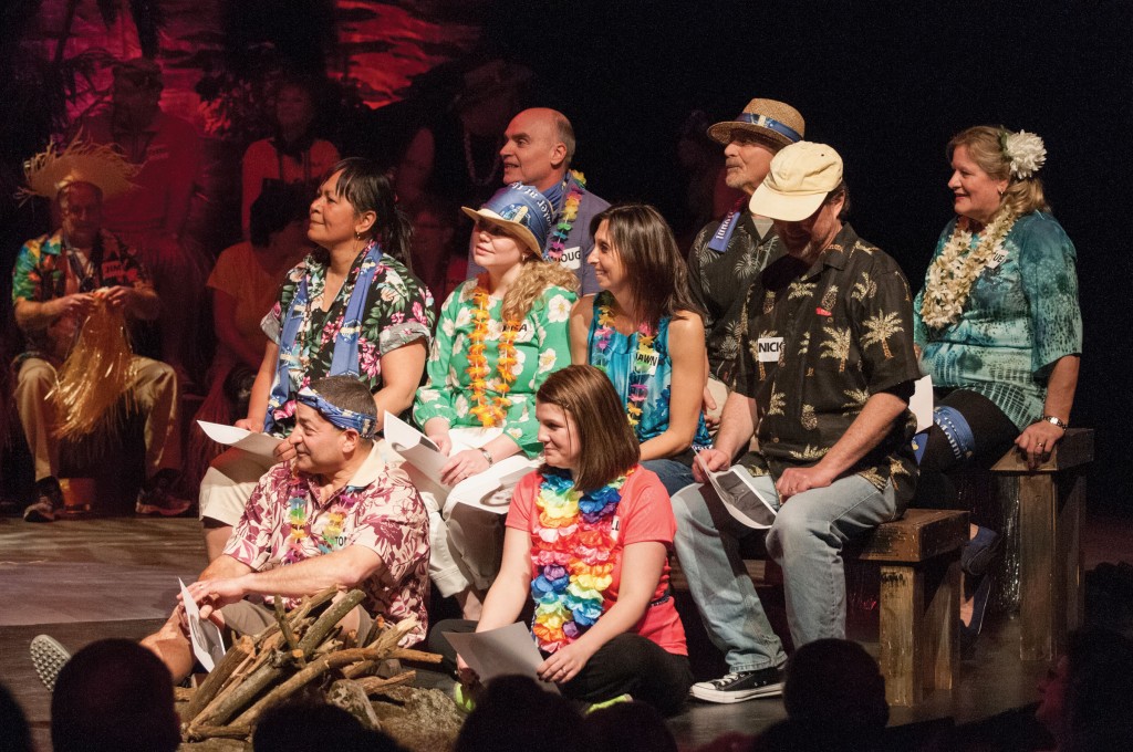 Group of Survivor participants on stage in Hawaiian shirts and leis