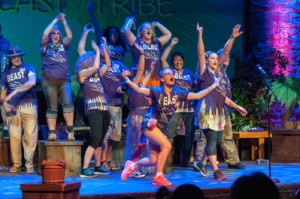 Scene from Survivor - group of excited participants with hands raised in the air