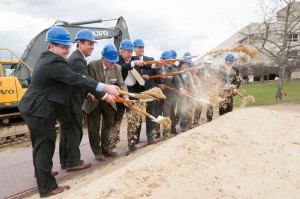 Community leaders with hardhats on shoveling dirt at the groundbreaking ceremony