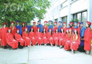 Group of graduates and red and blue caps and gowns outside the Gardner campus