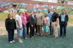 Group of students, faculty, community leaders in front of the mural