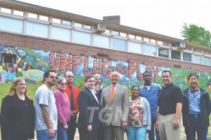 Group of students, faculty, community leaders in front of the mural