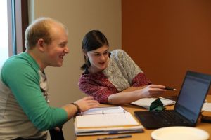 Two students work on a project on their laptop